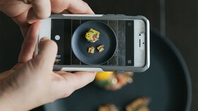 Kāds fotografē Šķīvis ar nevainojami pasniegtu izsmalcinātu ēdienu uzņemšana