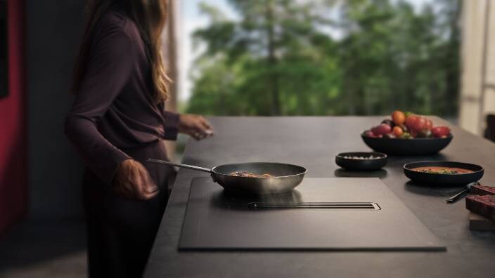 Dāma gatavo ēdienu pannā uz AEG SaphireMatt