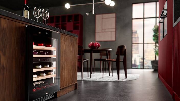 Skats uz virtuvi ar vīna pagrabu, kas piestiprināts pie virtuves galda, uz kura atrodas vīna glāzes.